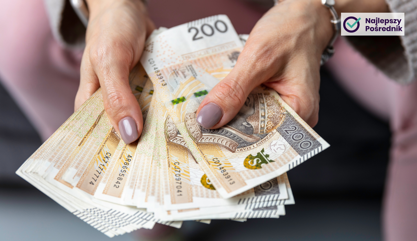 Zadbane kobiece dłonie trzymające plik banknotów o nominale 200 zł