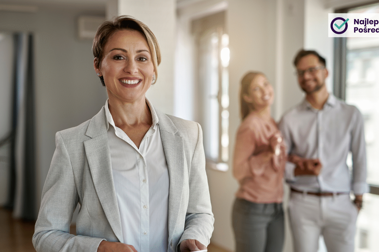 Na pierwszym planie uśmiechnięta agentka nieruchomości, na drugim planie szczęśliwe młode małżeństwo