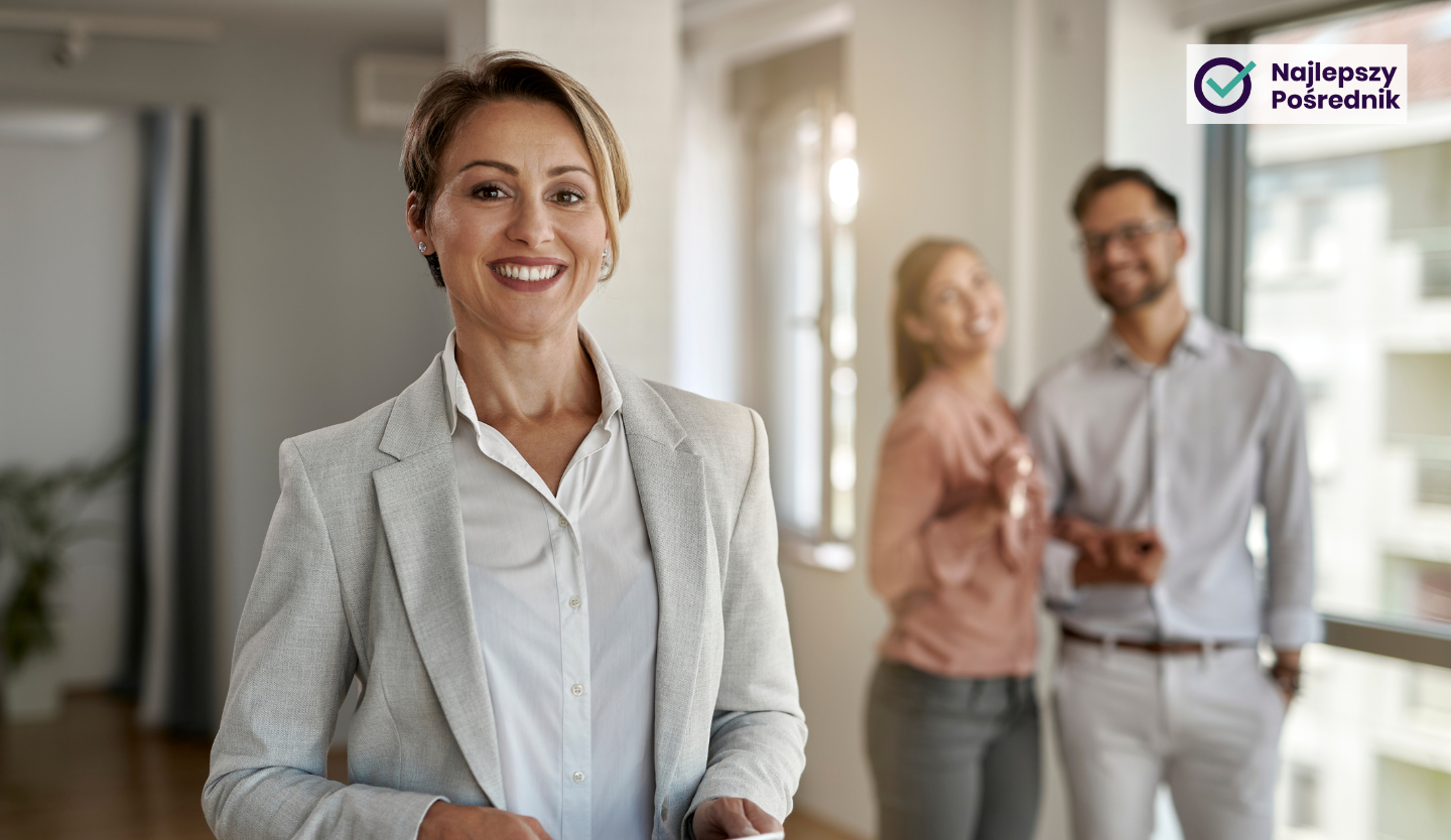 Na pierwszym planie uśmiechnięta agentka nieruchomości, na drugim planie szczęśliwe młode małżeństwo