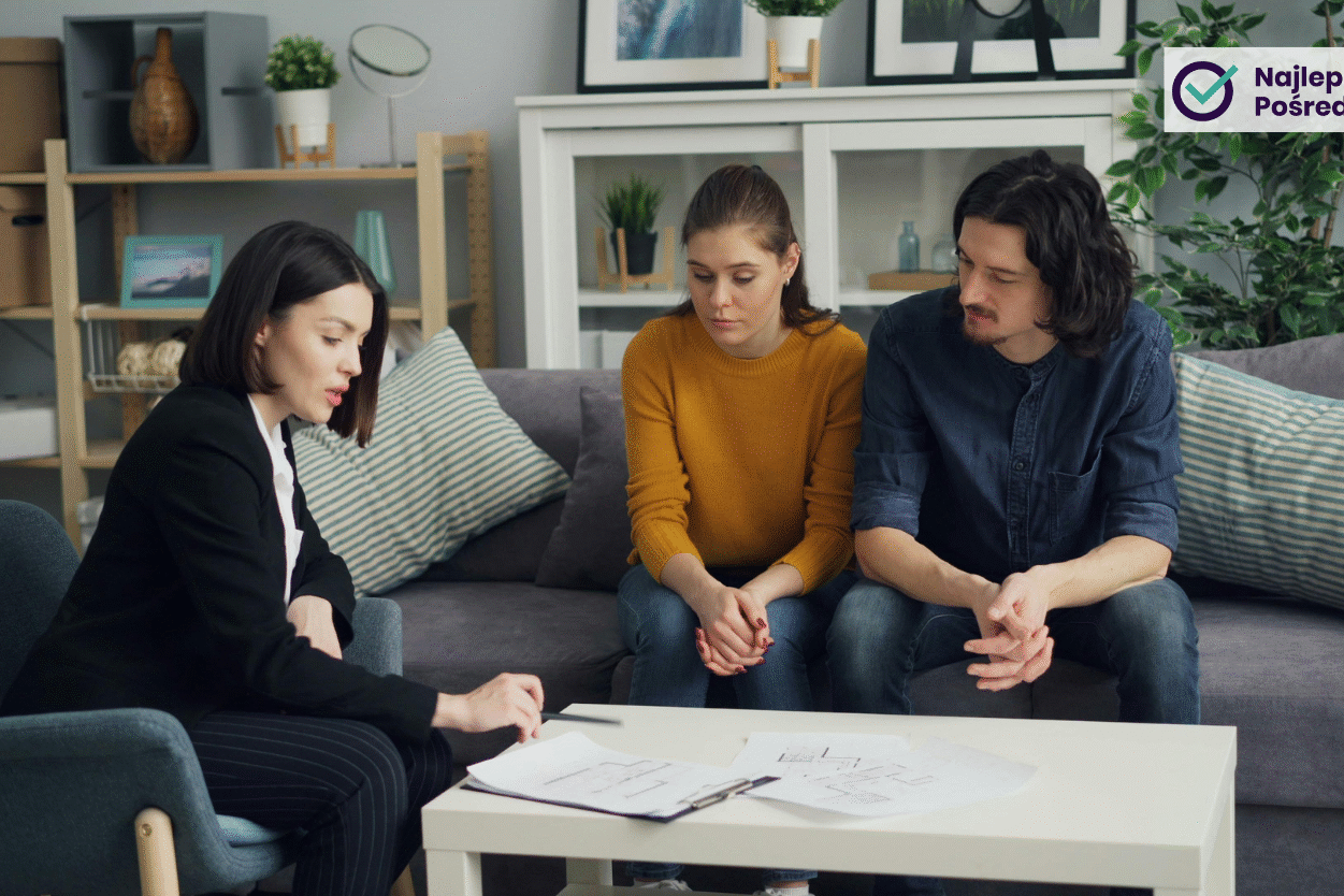 Kobieta agent nieruchomości tłumaczy coś parze kupującej mieszkanie