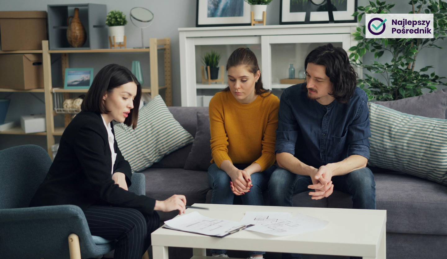 Kobieta agent nieruchomości tłumaczy coś parze kupującej mieszkanie