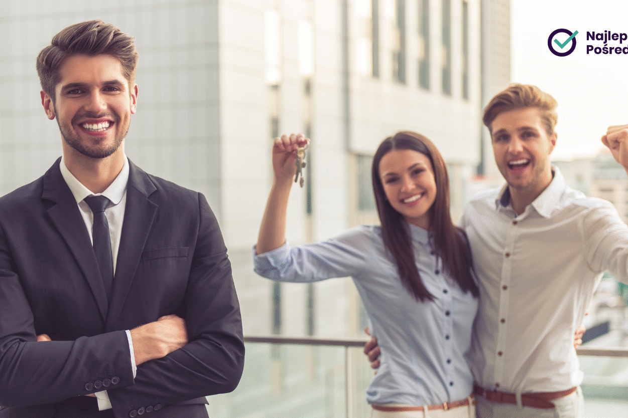 Uśmiechnięty pośrednik nieruchomości, a z tyłu młode entuzjastyczne małżeństwo